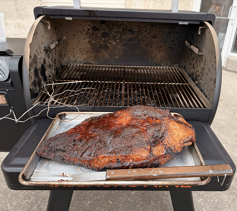 Finished brisket in front of a pellet grill
